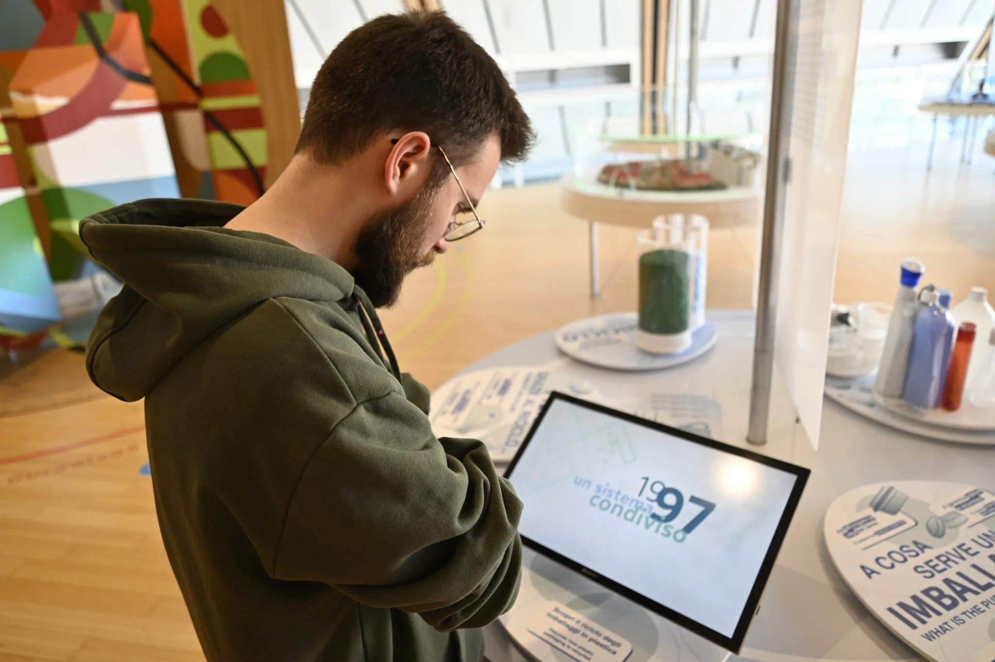 Un visitatore usa il monitor touch dell'exhibit sugli imballaggi in plastica