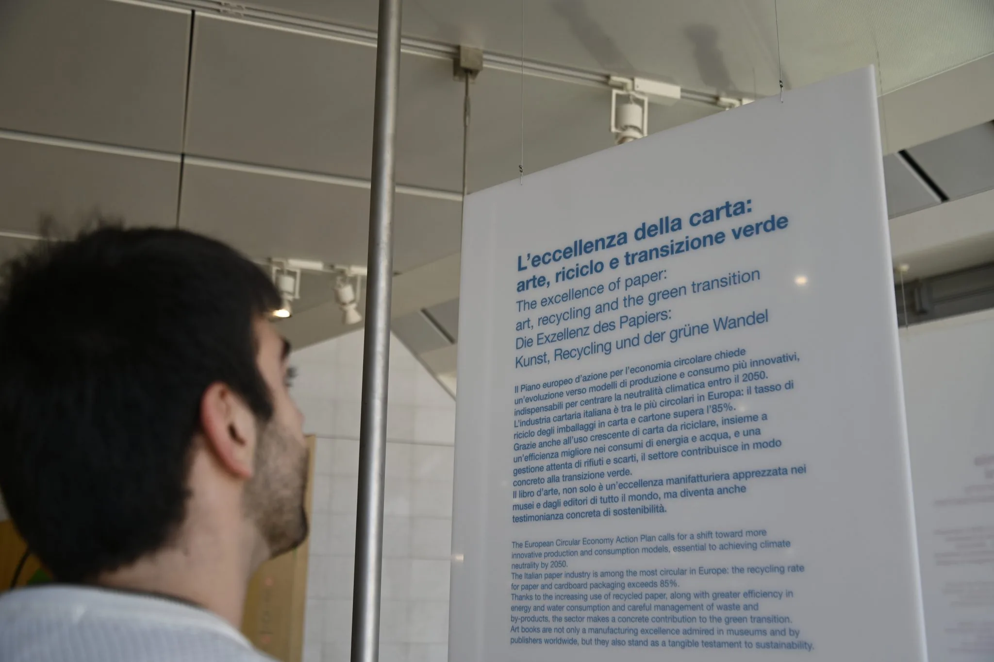 Un visitatore legge il pannello dell'exhibit sulla filiera della carta